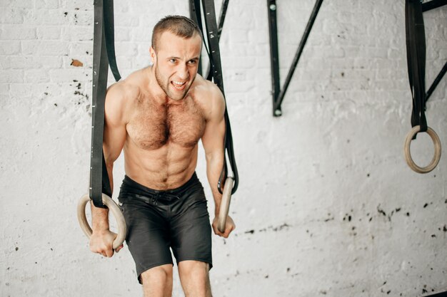 Monter l'homme tirant sur des anneaux de gymnastique.