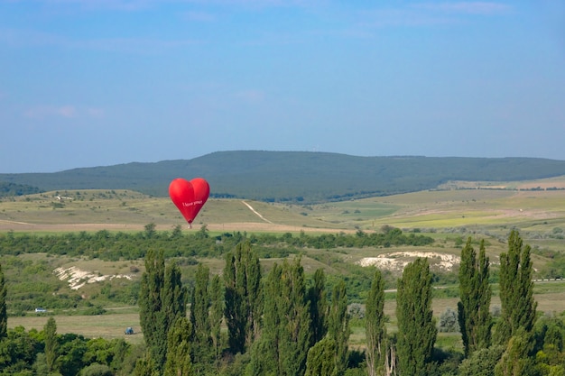 Montgolfière Ballon rouge en forme de coeur volant sur fond de Roche Blanche