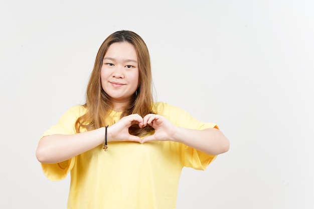 Montrant Le Signe D'amour De La Belle Femme Asiatique Portant Un T-shirt Jaune Isolé Sur Fond Blanc