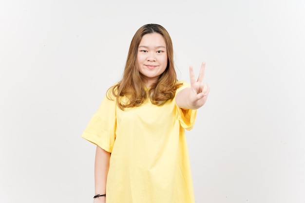 Montrant le signe de paix d'une belle femme asiatique portant un T-shirt jaune isolé sur fond blanc