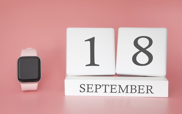 Montre moderne avec calendrier cube et date 18 septembre sur mur rose. Concept de vacances de temps d'automne.