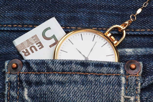 Montre de poche avec chaîne en jean et cinq euros. Fermer.