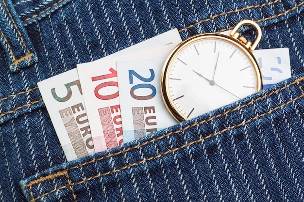 Montre de poche dans votre pantalon et jean avec de l'argent euro. Fermer.