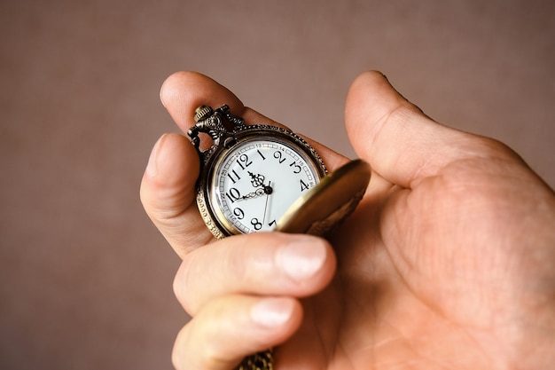 Une montre de poche entre les mains d'un homme