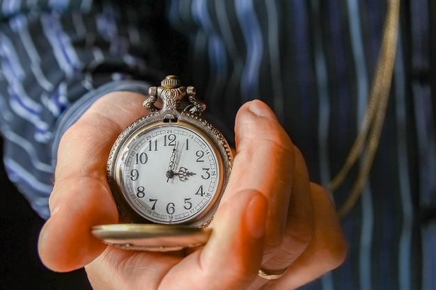 Une montre de poche entre les mains d'un homme