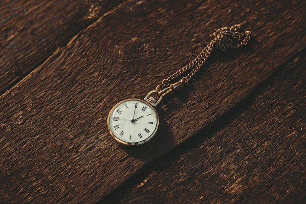 Montre de poche vintage sur une chaîne sur un fond en bois