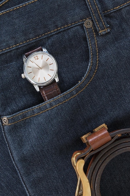 Une montre de poignet et une ceinture en cuir sur un jean