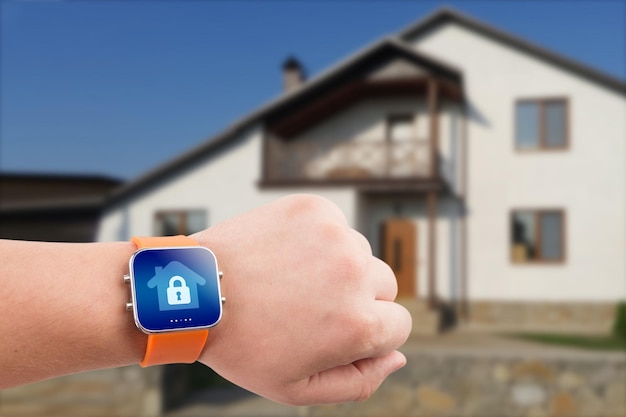 Montres intelligentes avec application de sécurité à domicile sur une main sur le fond du bâtiment