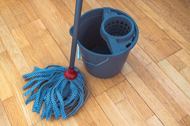 Mop avec buse à ruban et seau pour nettoyer le sol avec fonction d'essorage sur fond de parquet