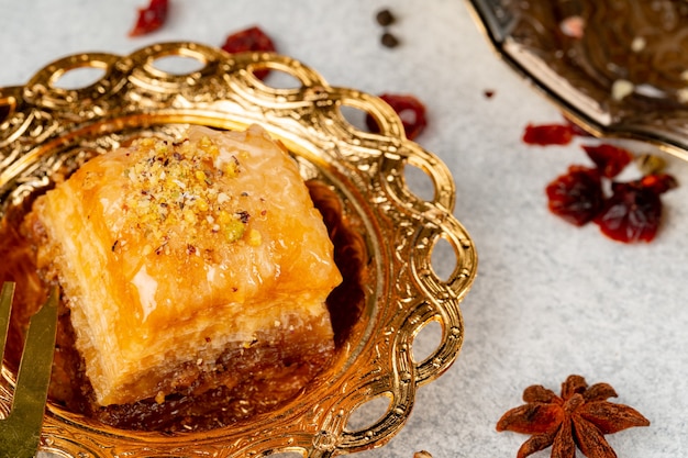 Morceau de baklava turc dans une assiette arabe dorée