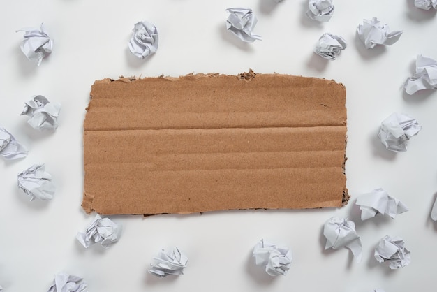 Morceau de carton avec un message important entouré de papier enveloppe une annonce cruciale sur du carton avec des notes froissées autour d'idées récentes présentées sur du carton épais