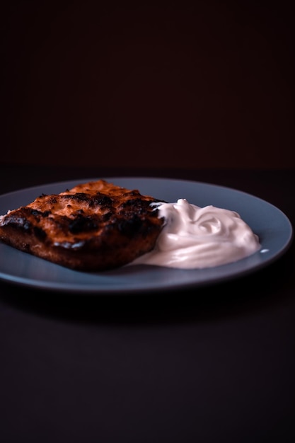 Un morceau de casserole avec de la crème sure sur une soucoupe