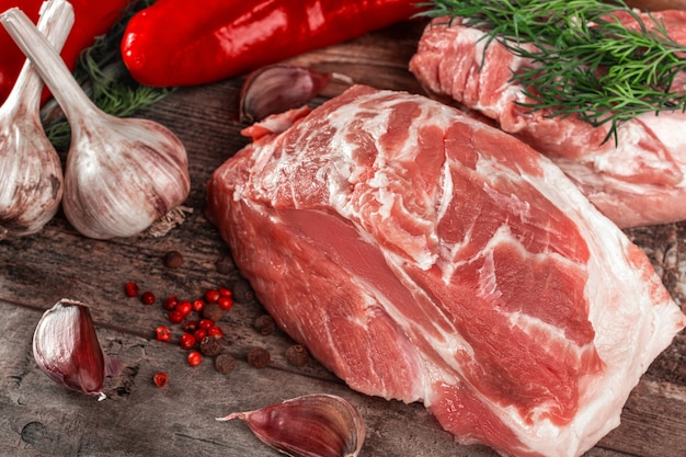 Photo morceau de cou de porc cru sur table en bois. filet de porc aux épices et romarin