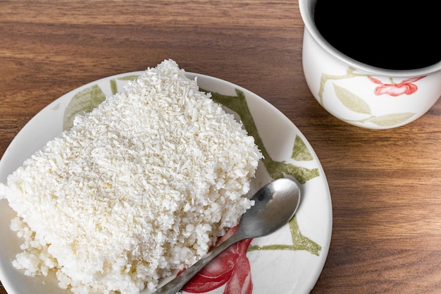 Morceau de couscous dans une soucoupe en porcelaine sur une table en bois plat brésilien typique à base de sucre de lait de tapioca et de lait de coco