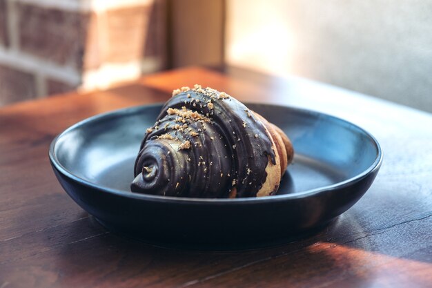Un morceau de croissant au chocolat dans une plaque noire sur table en bois en boulangerie
