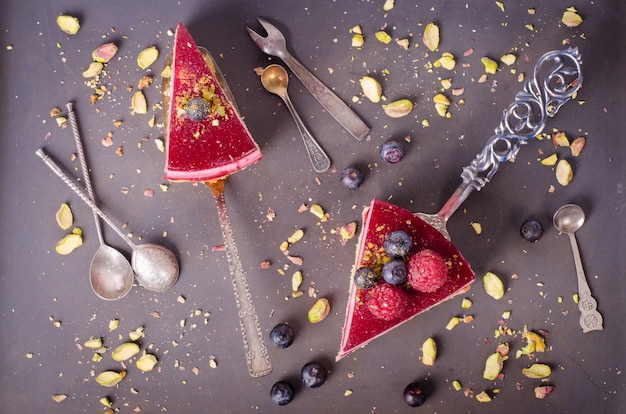 Morceau de délicieux gâteau aux framboises avec framboises fraîches, myrtilles, groseilles et pistaches à la pelle