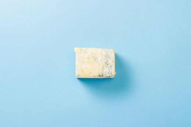 Un morceau de fromage bleu sur une surface bleue. Le minimalisme. Mise à plat, vue de dessus.