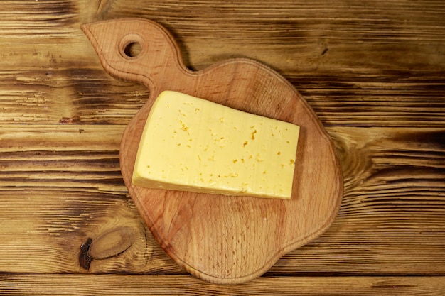 Morceau de fromage sur une planche à découper sur une table en bois