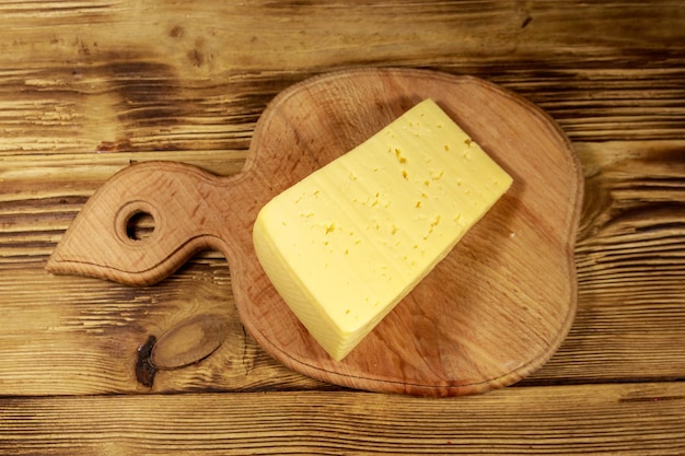 Morceau de fromage sur une planche à découper sur une table en bois