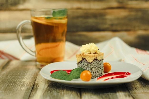 Un morceau de gâteau sur une assiette blanche et décoré de fruits et de sauces