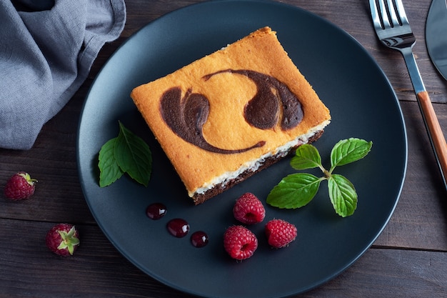 Un morceau de gâteau sur une assiette de brownies au chocolat et cheesecake caillé aux framboises