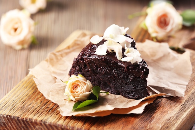 Morceau de gâteau au chocolat décoré de fleurs sur une table en bois marron