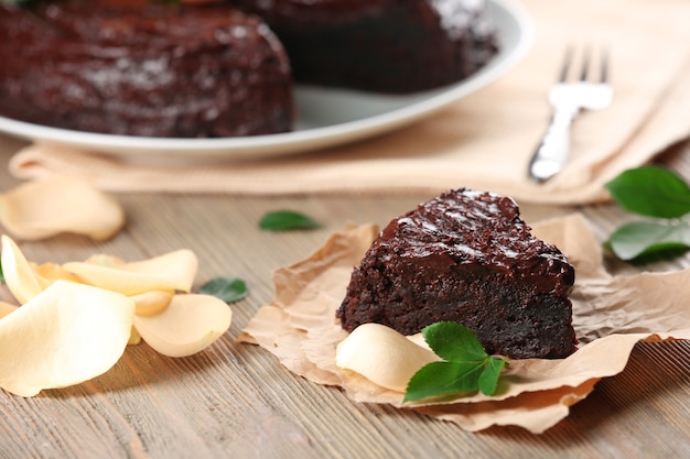 Photo morceau de gâteau au chocolat décoré de fleurs sur une table en bois marron