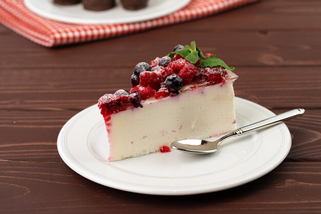 Morceau de gâteau au fromage aux baies servi sur une table en bois brun close up