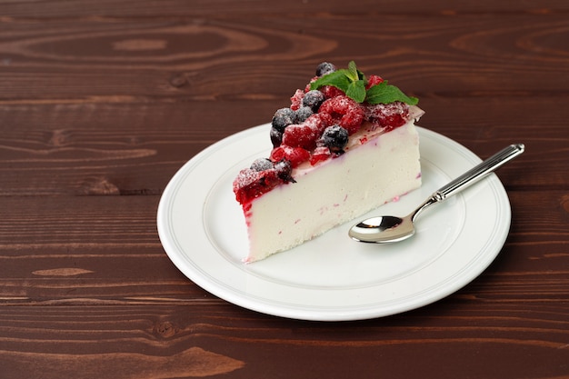 Morceau de gâteau au fromage aux baies servi sur une table en bois brun