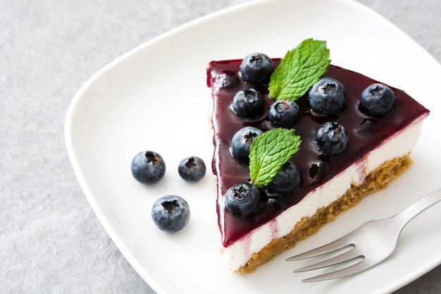 Morceau de gâteau au fromage aux bleuets sur pierre grise