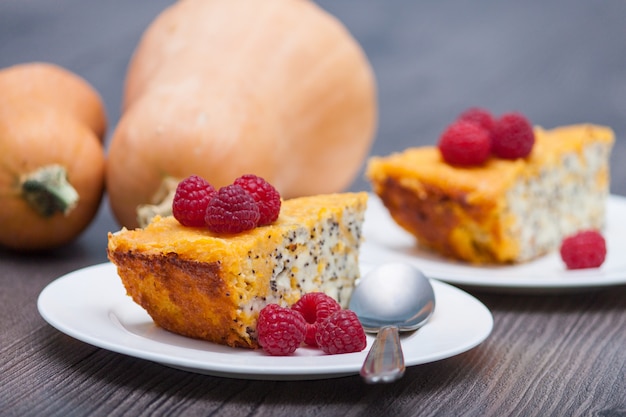 Morceau de gâteau au fromage fait maison citrouille avec framboises, coquelicot sur la table en bois. En bonne santé