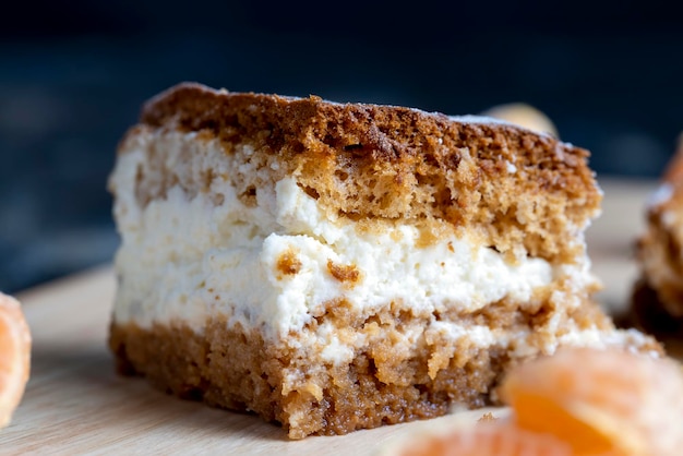 Un morceau de gâteau au miel avec crème à la vanille et mandarines aux agrumes