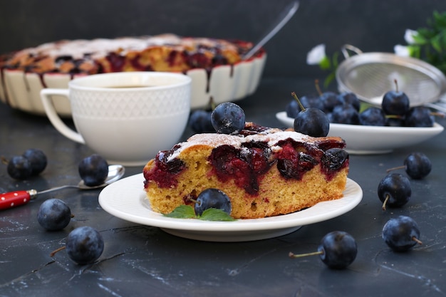 Morceau de gâteau aux baies de prunellier et tasse de café sur fond sombre