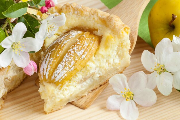 Morceau de gâteau aux pommes fait maison pomme fruits et branche d'arbre en fleurs sur la table de la cuisine