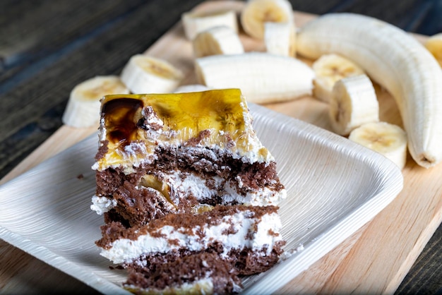 Un morceau de gâteau à la banane et de tranches de bananes fraîches dessert de crème au beurre de génoise sucrée avec bananes et garniture à la banane