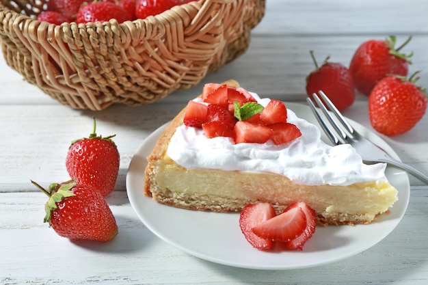 Morceau de gâteau avec crème et fraises sur assiette