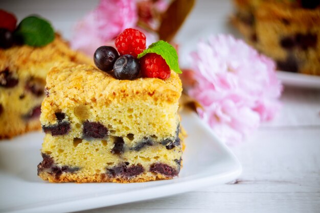 Morceau de gâteau à la crème sure aux bleuets sur une surface en bois blanche