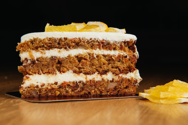 Morceau de gâteau éponge aux carottes savoureux fait maison avec crème pâtissière sur table en bois