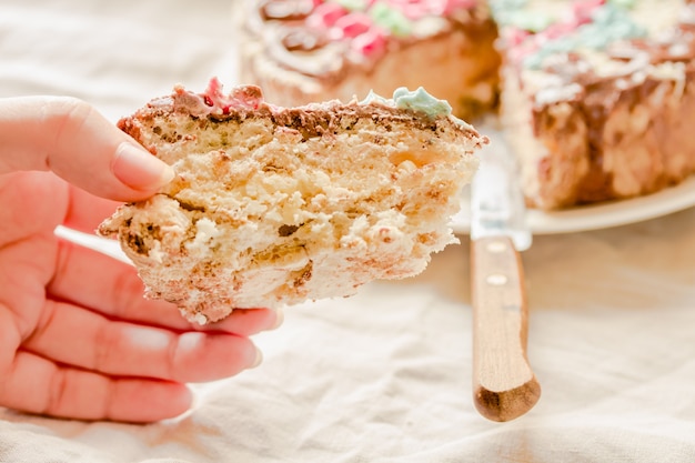 Un morceau de gâteau traditionnel de Kiev (Kiev) ou de meringue daquoise avec de la crème au beurre à la main d'une jeune femme. Bonbons de vacances savoureux.