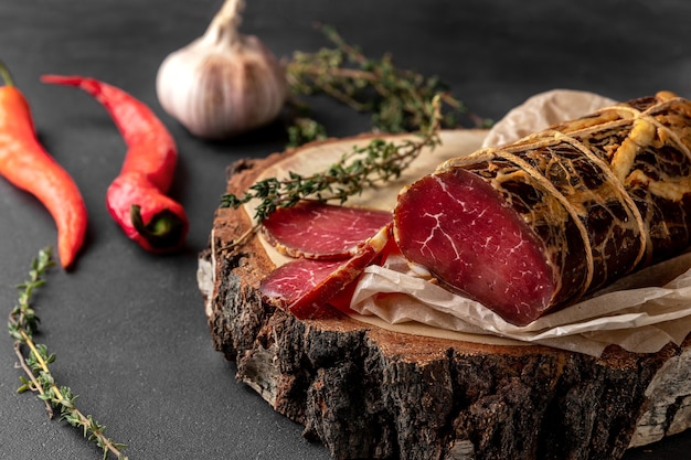 Morceau de jambon sec fumé rouge sur une coupe transversale en bois de l'arbre