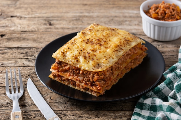 Morceau de lasagne à la viande sur plaque noire sur table en bois rustique