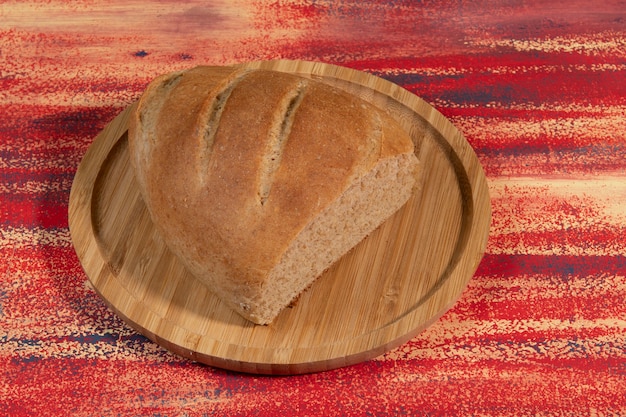 Morceau de pain fait maison coupé sur un plateau en bambou sur une table rustique