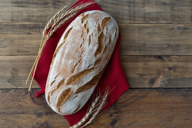 Morceau de pain rustique sur fond de bois avec des ornements d'épis de blé Copy space