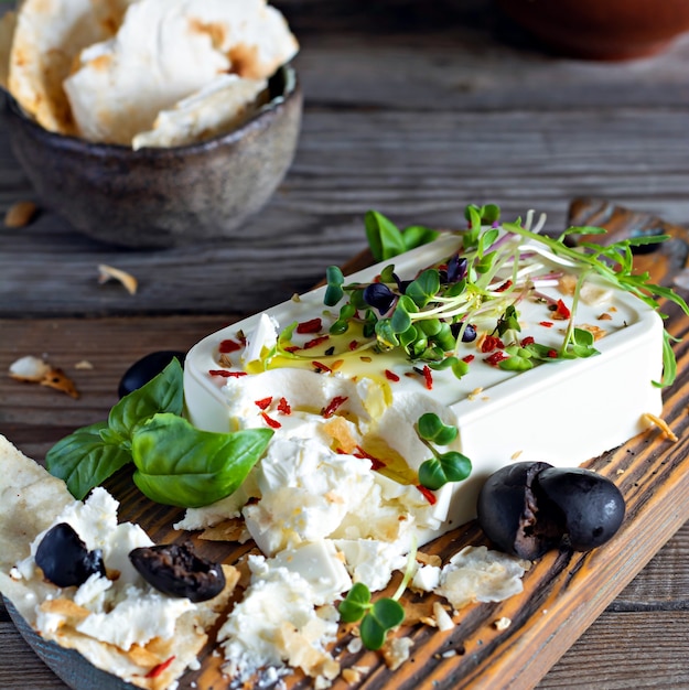 Un morceau de paneer de feta frais avec des olives, des herbes, des épices et des tranches de pain plat