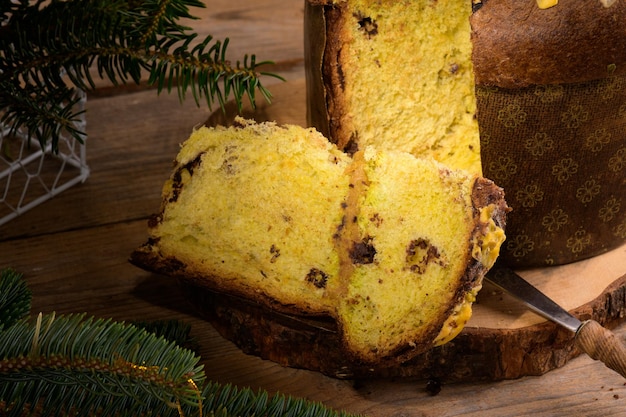 Morceau de panettone italien traditionnel de gâteau de Noël avec l'arc vert sur le fond rustique en bois