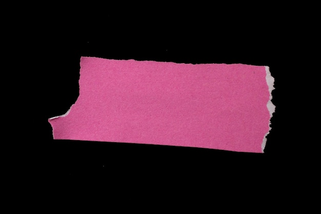 Morceau de papier déchiré rose isolé sur fond noir avec espace de copie pour le texte