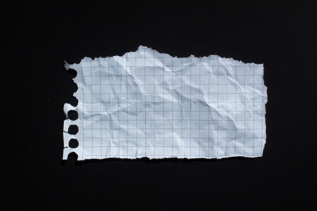 Un morceau de papier avec un morceau de papier déchiré sur un fond noir.