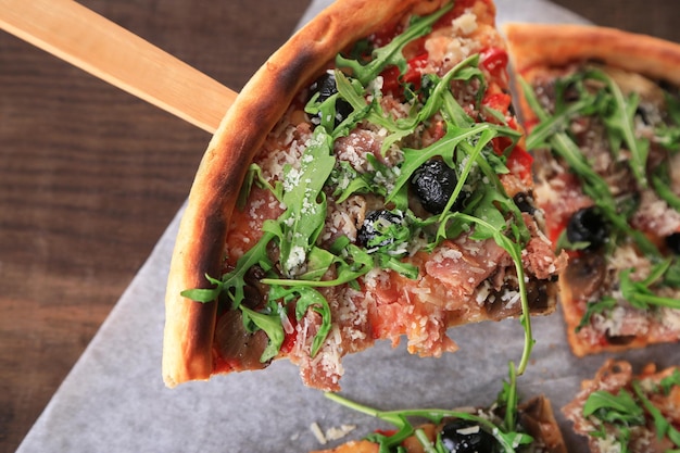 Photo morceau de pizza à la roquette sur une spatule en bois libre