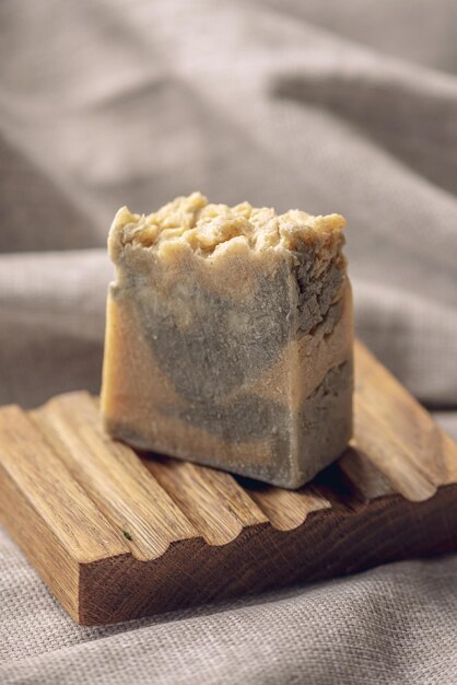 Photo un morceau de savon naturel artisanal sur une plaque de savon en bois et un tissu de coton léger