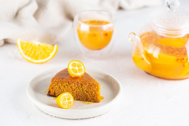 Un morceau de tarte à l'argousier maison mannik à l'orange décoré de kumquat avec du thé